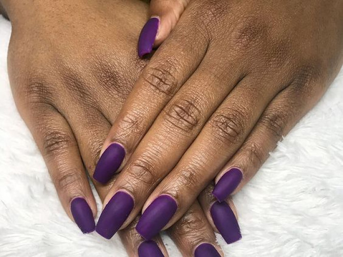 Uñas de color morado mate sobre piel morena oscura